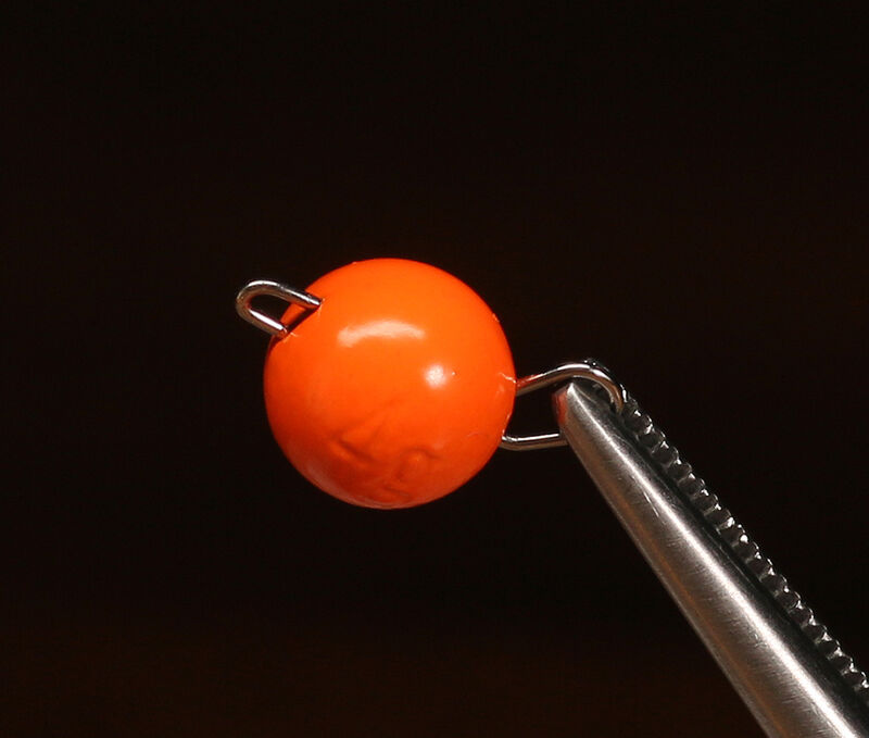 Size 1 Hareline Insta Jig 2.0 tungsten weights in Fl. Orange #137, showcasing the 0.6-gram keeled bodies coated in a high-visibility, smooth neon orange finish held on a vice.