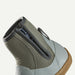 Close-up of the side and heel of a mid-calf slip-on shoe with a textured olive green knit collar, a light gray synthetic upper, and a brown gum sole, shown against a plain off-white background.