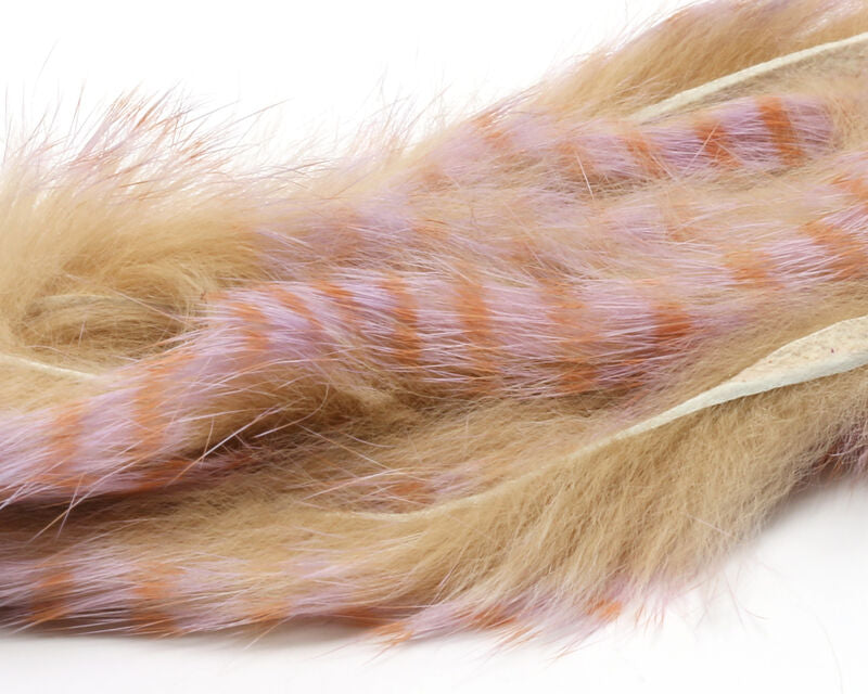 A package of Hareline Barred Polychrome Rabbit Strips in Tan, Pale Purple, and Pale Rust #6, showcasing the soft rabbit fur strips with a variegated tan and lavender body overlaid with rich, rusty-red barred markings.