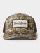 Front view of the Duck Camp Trucker Hat in Midland camo pattern, highlighting the structured front panels, the retro brown and white Duck Camp Premium Outdoor Goods logo patch, and the matching dark brown mesh back.
