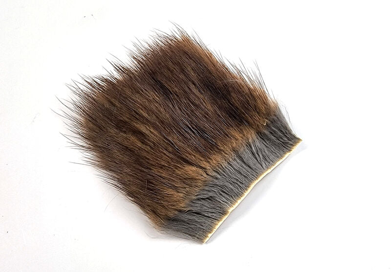 A rectangular piece of natural Hareline American Muskrat Fur showing the dense, soft grey underfur mixed with dark brown guard hairs attached to a clean tan hide back.