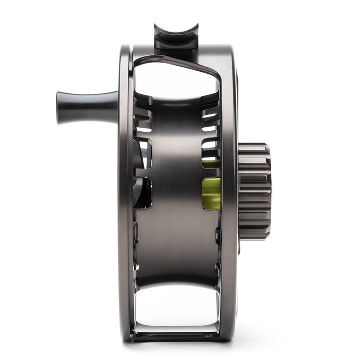 A close-up side view of a dark gray metallic fly fishing reel with a black handle and a small lime green accent, set against a solid white background.