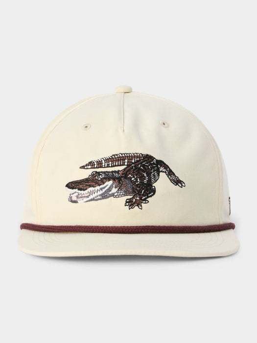 Beige cap with an alligator design on a white background