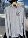 Feather Grey Patagonia Capilene Cool Daily Hoody hanging up, featuring the clean black circular trout fly logo on the left chest.