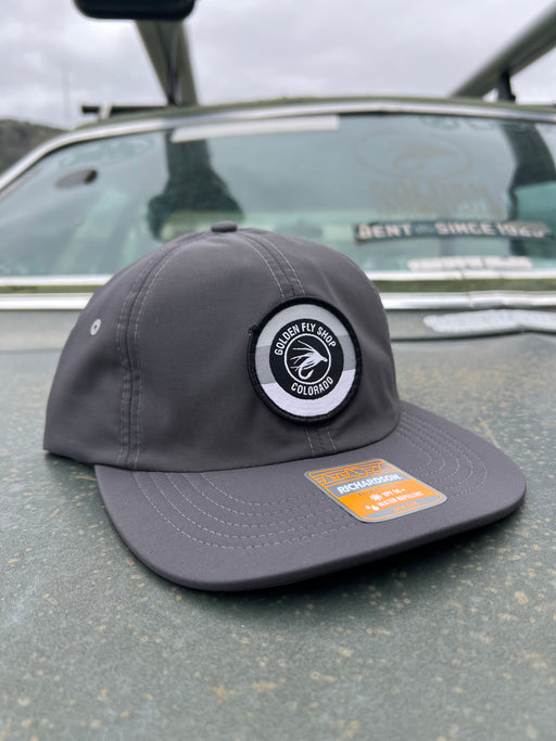 Golden Fly Shop 934 Hat Wildwood Charcoal 2026 edition water-repellent performance cap featuring a circular embroidered fly logo patch on a gray Richardson frame