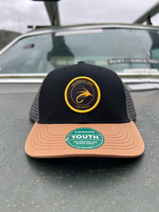 Golden Fly Shop Youth Trucker Hat Black Caramel Dark Grey 2026 edition mesh snapback cap featuring a circular gold embroidered fly silhouette logo patch