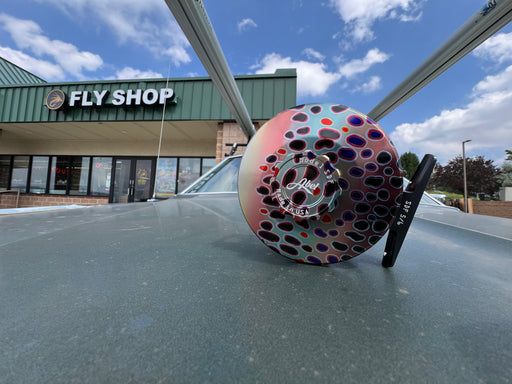 Abel SDF 5/6 fly reel featuring the custom hand-anodized Native Trout solid graphic finish resting on a vehicle hood outside the Golden Fly Shop
