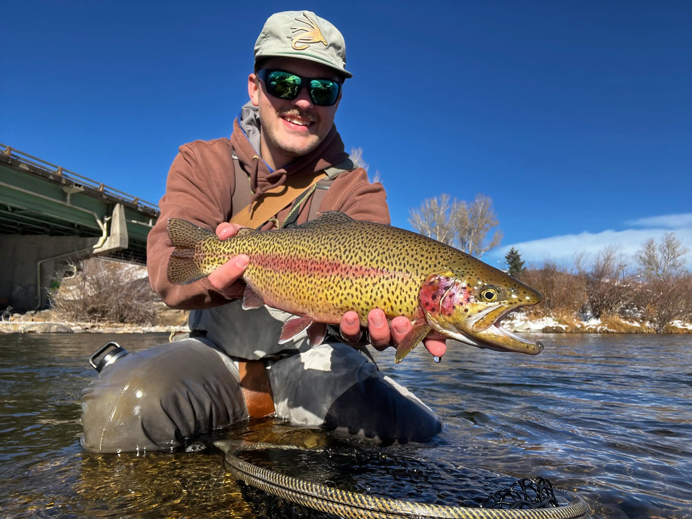 Holding a trout on a river with a snowy background.