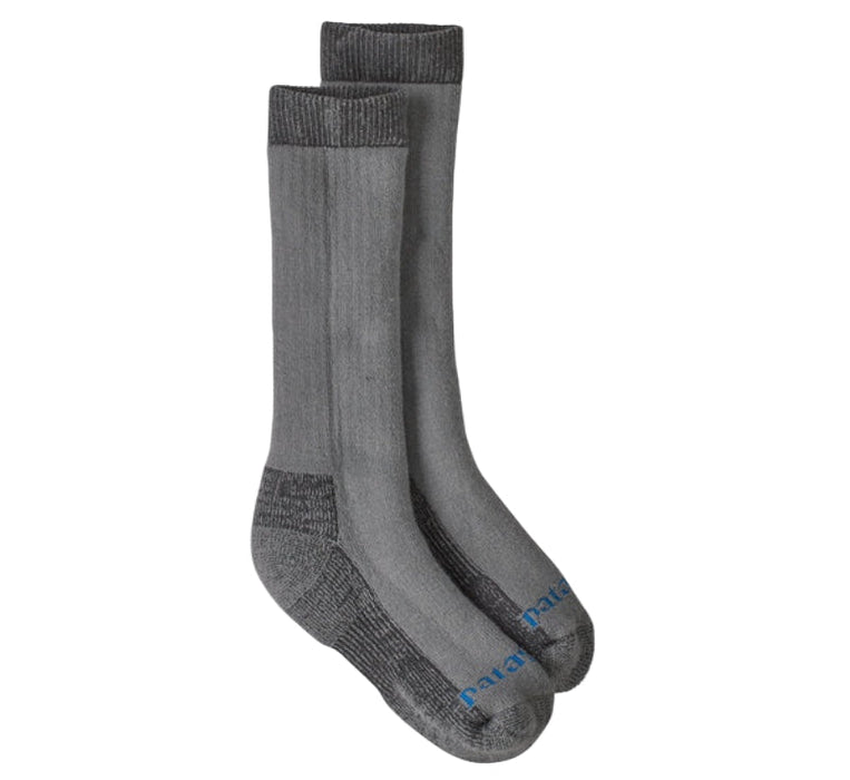 A pair of Patagonia crew socks in heather gray with darker gray reinforced zones at the heel, toe, and sole, featuring a small blue Patagonia logo on the toes, shown against a plain white background.
