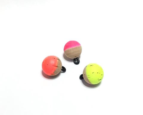 Three CorQs natural cork fly fishing strike indicators in high-visibility neon pink, orange, and chartreuse.