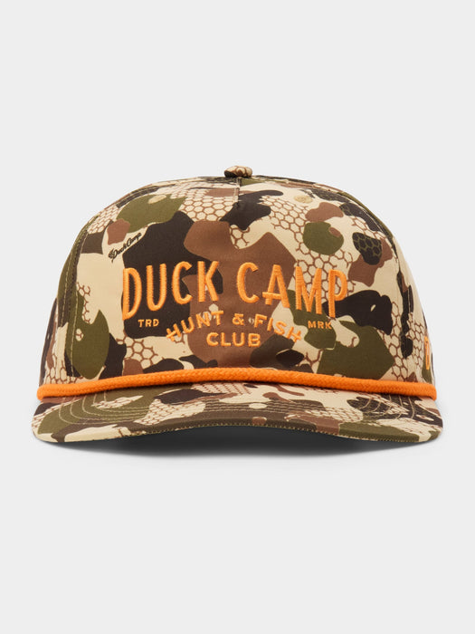 A camouflage snapback cap with orange embroidered 'DUCK CAMP' lettering on the front and a matching orange accent line along the brim, shown against a light gray background.