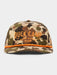 A camouflage snapback cap with orange embroidered 'DUCK CAMP' lettering on the front and a matching orange accent line along the brim, shown against a light gray background.