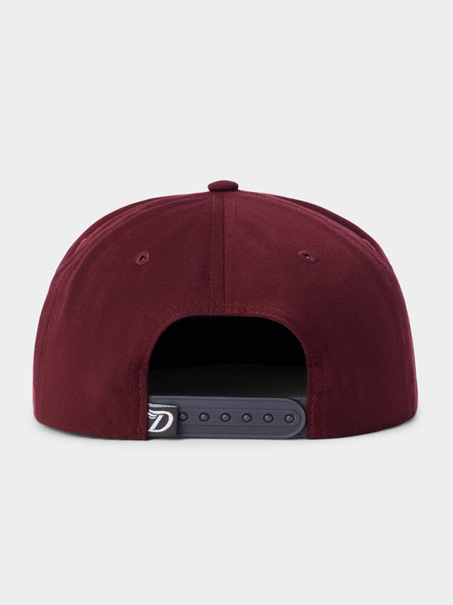 A close-up rear view of a structured snapback cap in burgundy, showing the dark gray adjustable strap closure with a small white logo patch.