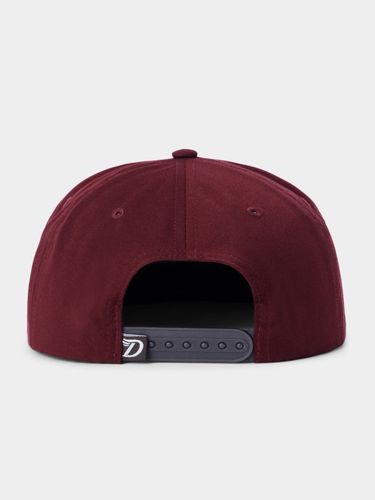 A close-up rear view of a structured snapback cap in burgundy, showing the dark gray adjustable strap closure with a small white logo patch.
