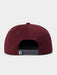A close-up rear view of a structured snapback cap in burgundy, showing the dark gray adjustable strap closure with a small white logo patch.