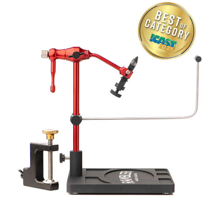The Rambler Co. Nomad Fly Tying Vise in Rambler Red anodized aluminum, mounted on its black pedestal base alongside the included c-clamp accessory, featuring a gold ICAST 2025 Best of Category award badge overlay.