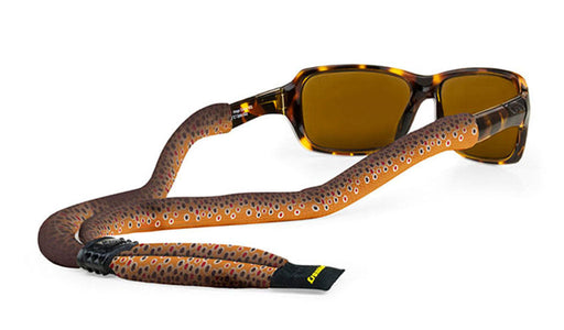 Croakies Suiters Collection Prints eyewear retainer in Brown Trout Fish Skin pattern, displaying a golden-brown knitted polyester strap with realistic red and black fish spotting attached to tortoise sunglasses.