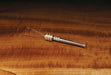 The Stonfo Rotodubbing #2 Split Twister tool featuring a knurled cylindrical silver handle, ball-bearing joint, and split wire loop prongs resting horizontally on a polished wood grain bench.