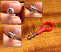 The Stonfo Thread Splitter tool featuring a bright red circular finger loop handle and a polished silver micro-needle tip, displayed alongside three step-by-step macro images demonstrating how to split orange fly tying thread.