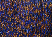 A close-up view of Hareline Grizzly Krystal Flash in Copper and Blue, showing a dense bundle of crinkled, highly reflective strands twisted with alternating metallic copper and deep blue segments.