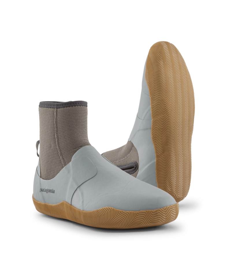 A pair of water shoes by Patagonia, featuring a white upper, a beige sock-like ankle collar, and a tan wavy-patterned sole, shown against a solid green background.