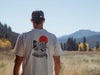 Angler looking out over a river wearing the ivory heavyweight Yakoda Rise Early fly fishing shirt showing the back artwork.